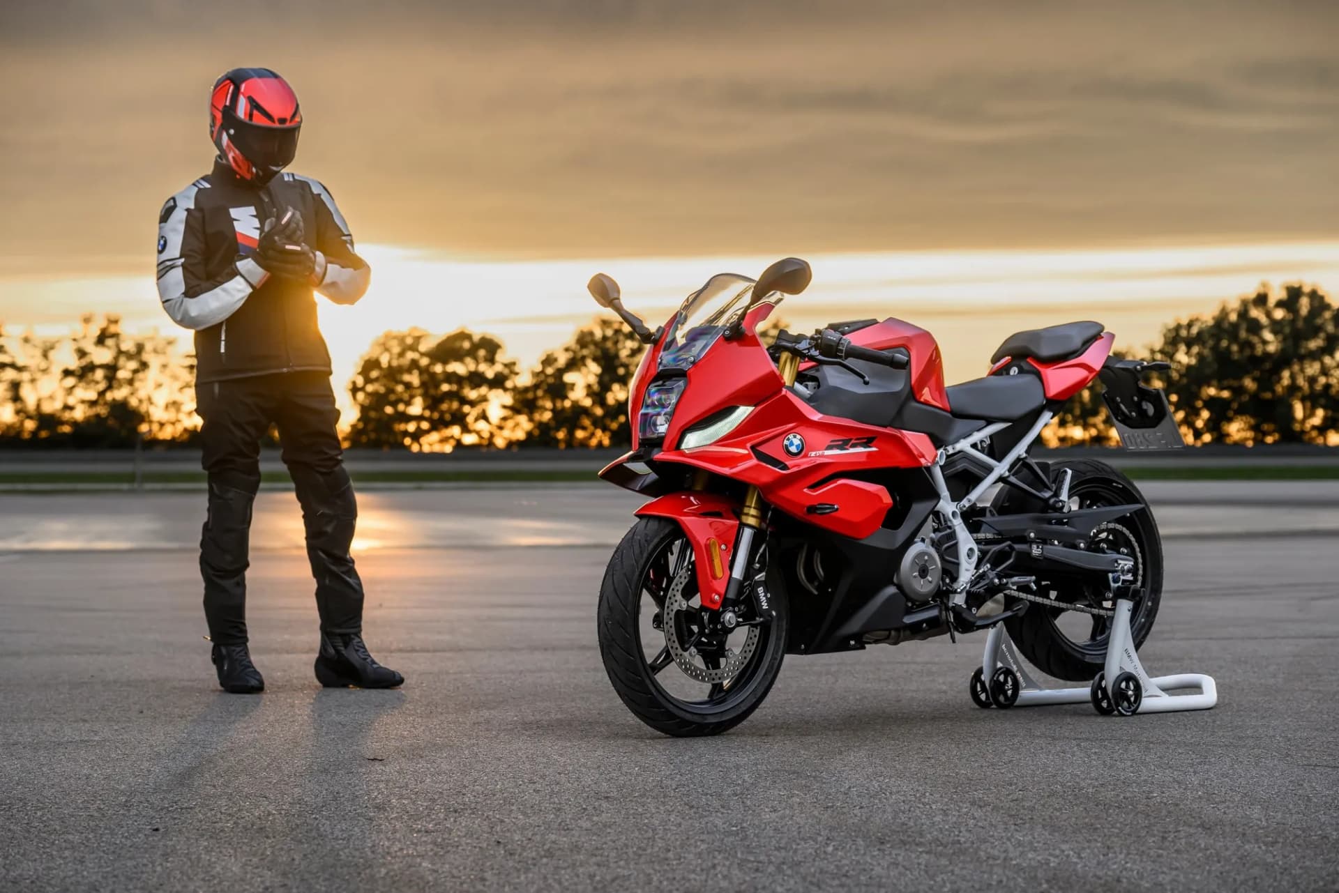 Motorkár v prilbe pri červenom superšporte BMW F 450 RR pri západe slnka