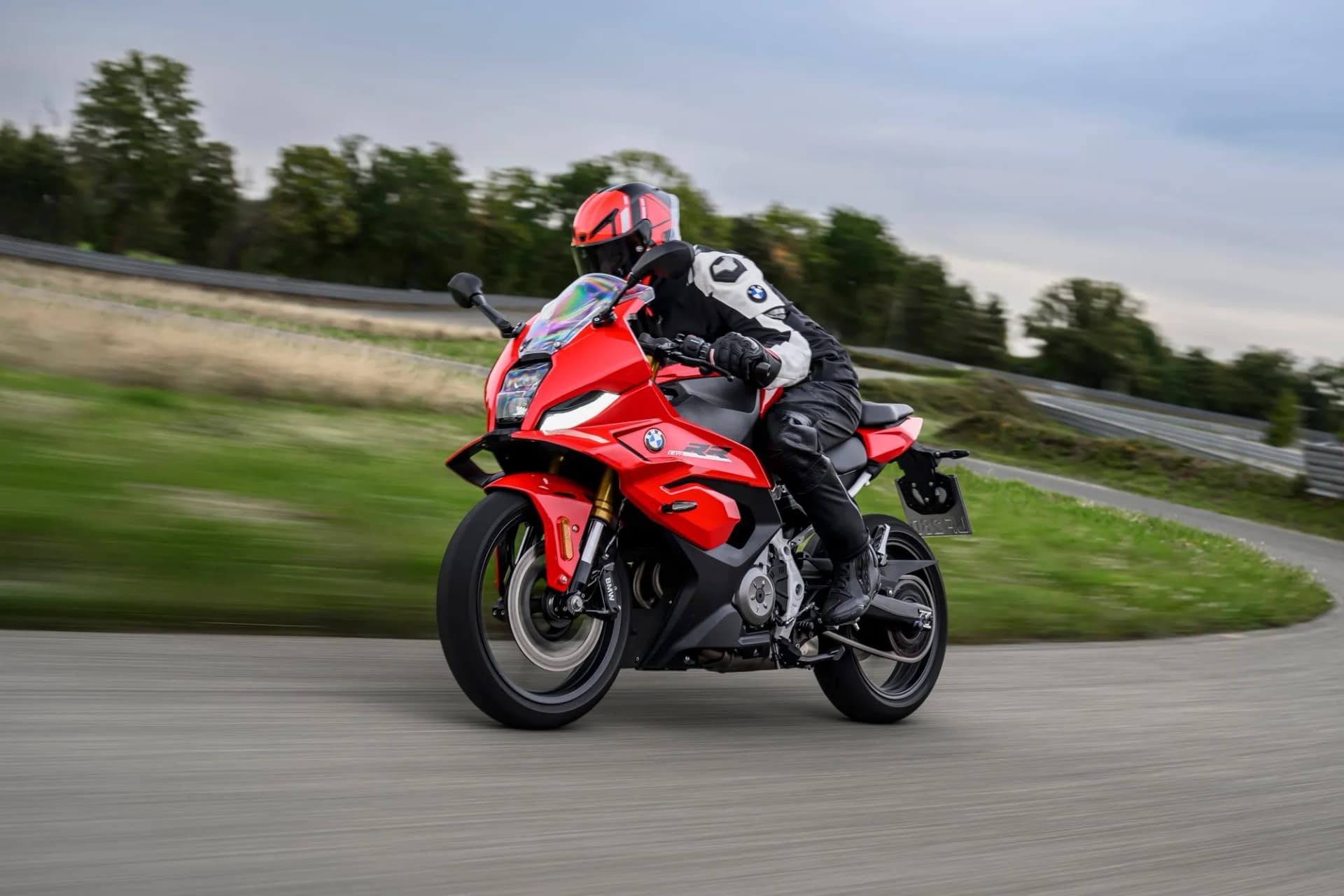 Motorkár v červenej prilbe v zákrute na červenej športovej motorke BMW RR na asfaltovom okruhu