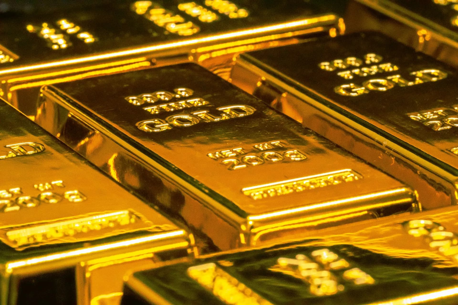 Zlaté tehly Argor-Heraeus s označením 1 kilo fine gold 999.9 a zlaté mince v detailnom zábere