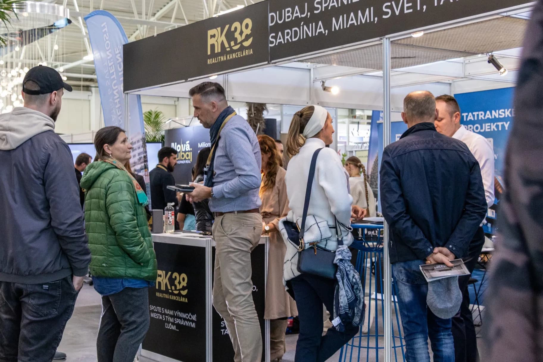Dav ľudí prechádza halou okolo výstavných stánkov