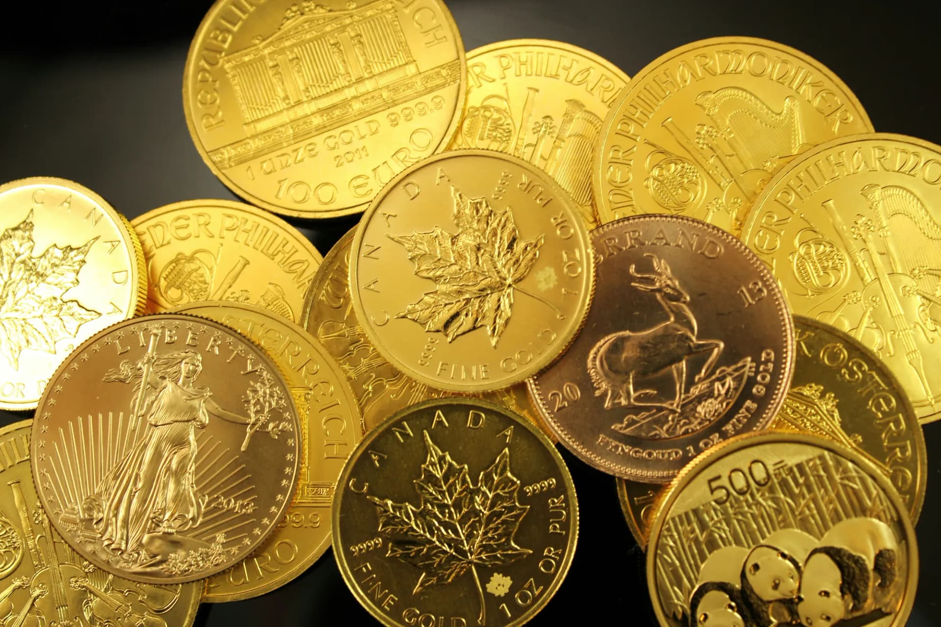 Hŕba zlatých mincí, medzi nimi Wiener Philharmoniker, kanadský javorový list, Krugerrand a Panda